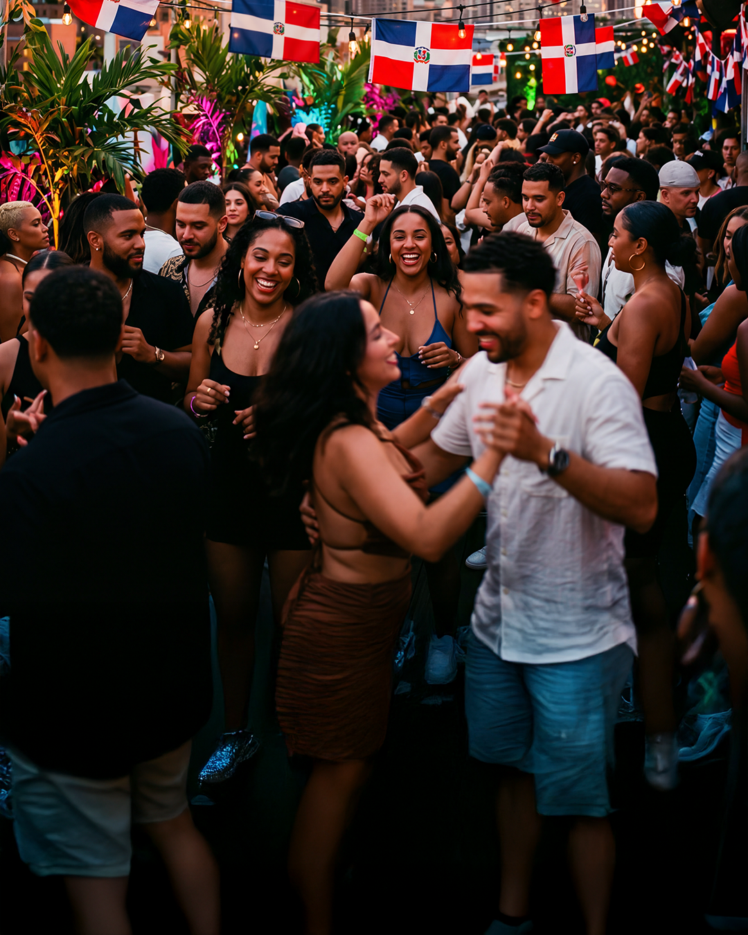 Dominicana party crowd dancing under string lights and Dominican flags at golden hour